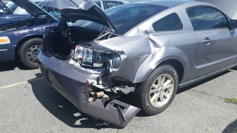 2001 Ford Crown Victoria - Photo of a wrecked silver coupe with front-end collision damage, not a document.