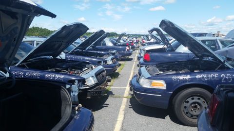 2001 Ford Crown Victoria - Photo of police-package sedans with open hoods lined up in a lot, not a document.