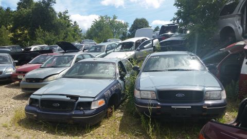 2001 Ford Crown Victoria - Photo of salvage vehicles parked in an outdoor yard, not a document.