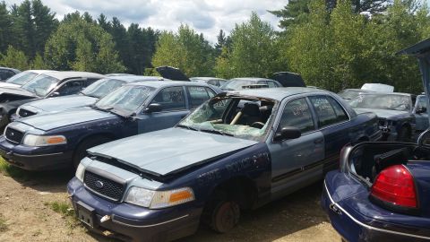 2001 Ford Crown Victoria - Photo of wrecked vehicles in an outdoor salvage yard, not a document.
