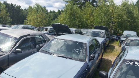 2001 Ford Crown Victoria - Photo of salvage sedans packed together in an outdoor yard, not a document.