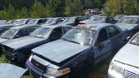 2001 Ford Crown Victoria - Photo of marked salvage sedans parked in an outdoor yard, not a document.