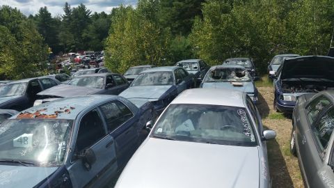 2001 Ford Crown Victoria - Photo of salvage vehicles with numbered windshields in an outdoor yard, not a document.