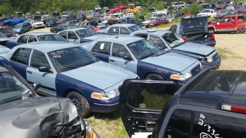 2001 Ford Crown Victoria - Photo of police-package sedans packed in a salvage yard, not a document.