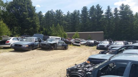 2001 Ford Crown Victoria - Photo of salvage vehicles parked near a metal building outdoors, not a document.