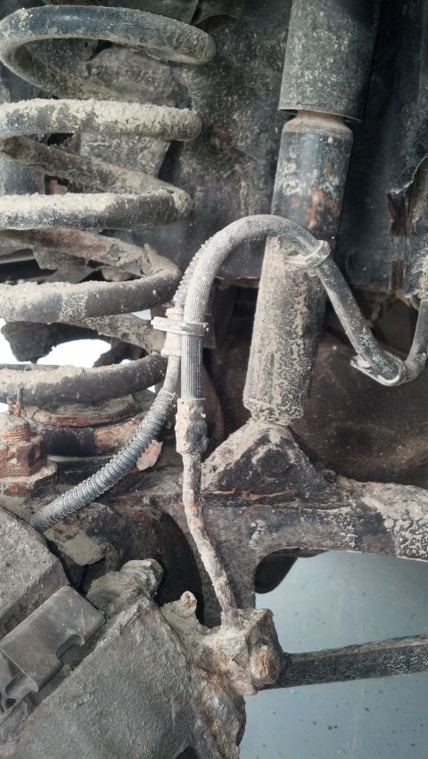 1996 Ford Bronco - This close-up image shows the heavily corroded suspension components of a 1996 Ford Bronco, including a coil spring, shock absorber, and br…