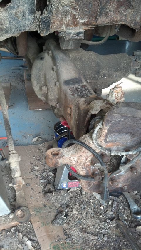 1996 Ford Bronco - A heavily rusted front differential and suspension components of a vehicle are shown, supported by a jack stand. The scene appears to be a…