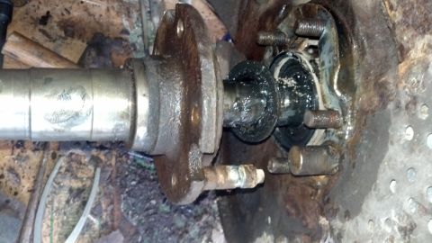 1996 Ford Bronco - This is a close-up, detailed view of a heavily greased and rusted automotive axle assembly, likely from a 1996 Ford Bronco, showing a beari…