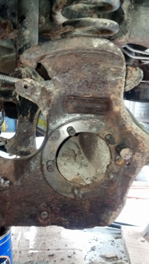 1996 Ford Bronco - This is a close-up, low-angle shot of heavily rusted suspension components on a vehicle. Visible parts include a coil spring, a knuckle or…