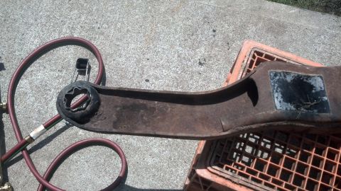 1996 Ford Bronco - A rusty metal part, possibly a vehicle component, rests on an orange plastic crate. A red and green hose is coiled nearby on a concrete sur…