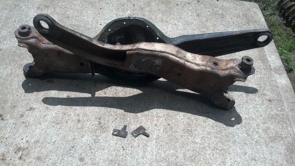 Rusty differential housing and control arm assembly with small brackets.