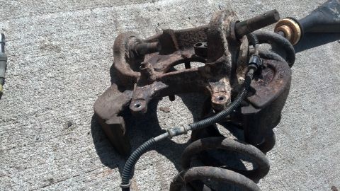 1996 Ford Bronco - A heavily rusted front suspension assembly, likely from a 1996 Ford Bronco, is shown resting on a concrete surface. The assembly includes a…