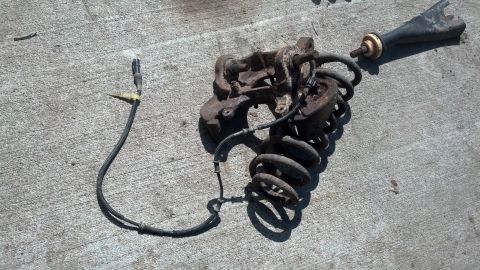 1996 Ford Bronco - A rusty suspension assembly, including a coil spring, shock absorber, and control arm, is laid out on a concrete surface.
