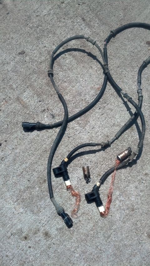 1996 Ford Bronco - Two automotive ABS speed sensor wires with connectors are laid out on a concrete surface. One connector is black and gray, while the other…