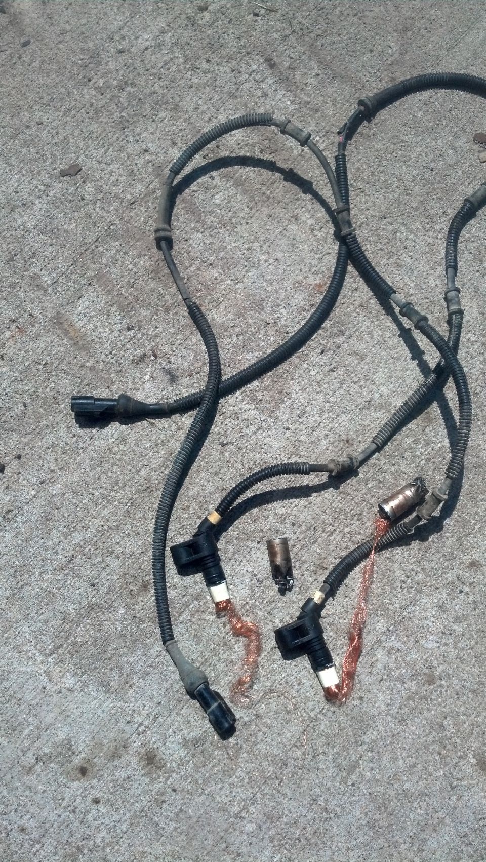 Automotive ABS speed sensor wires with connectors on concrete.