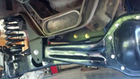 1996 Ford Bronco - A close-up view of the rear axle and suspension components of a vehicle, likely a 1996 Ford Bronco, showing a black differential housing, a…