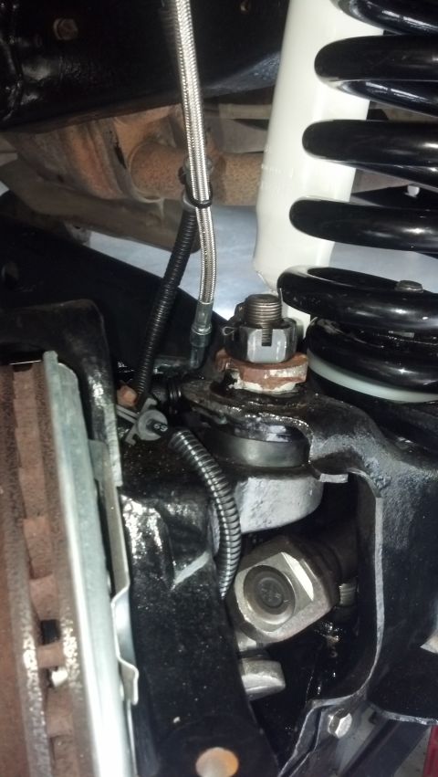 1996 Ford Bronco - A close-up view of the suspension components of a 1996 Ford Bronco, including a black coil spring, white shock absorber, and a ball joint a…