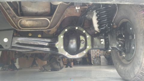 1996 Ford Bronco - Underside view of the rear axle and suspension components of a vehicle, likely a Ford Bronco, with a black differential cover and a black c…
