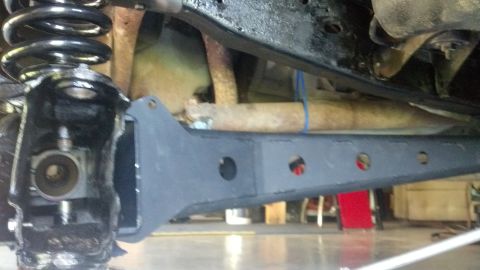 1996 Ford Bronco - A close-up view of the undercarriage of a vehicle, focusing on the suspension and a modified control arm. The control arm is painted black…