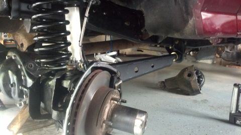 1996 Ford Bronco - The underside of a vehicle is shown, focusing on the suspension system. A large black coil spring and shock absorber are visible, along wit…