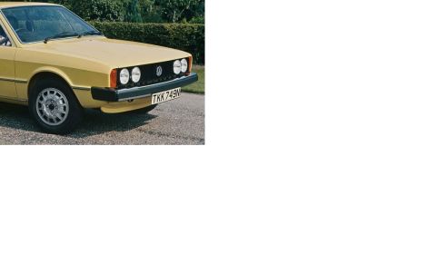 1973 Ford Ranchero - The front quarter view of a yellow Volkswagen Scirocco is shown parked on a gravel surface with a hedge in the background. The car has dual…