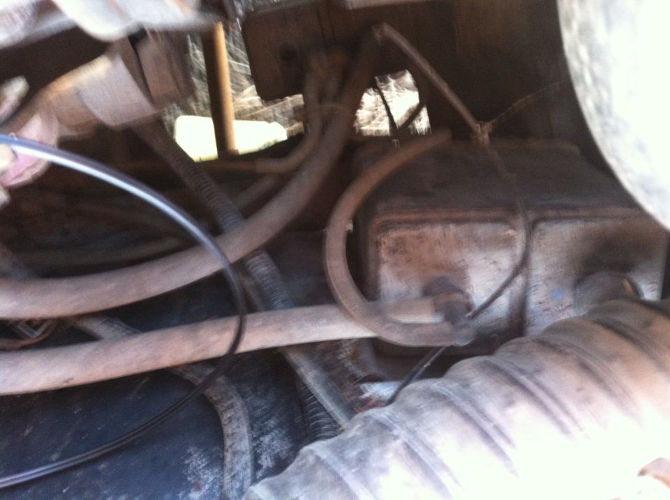 Close-up of vehicle engine bay with hoses, wires, and brake fluid reservoir.