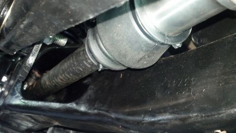 1996 Ford Bronco - A close-up view shows a rubber boot and a ribbed shaft, likely part of a steering or suspension system, attached to a black metal component…
