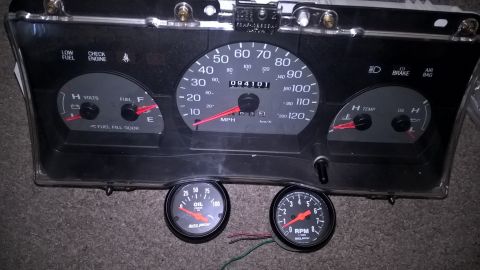 2004 Ford Crown Victoria - A black automotive instrument cluster with a speedometer, fuel gauge, voltmeter, temperature gauge, oil pressure gauge, and tachometer is d…