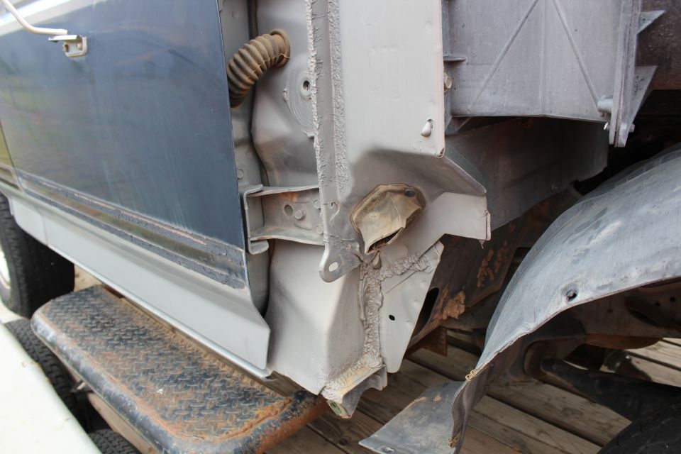 Damaged rear fender and door jamb of a dark blue vehicle.