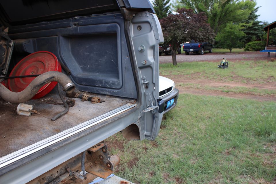 Open rear cargo area of a vehicle with parts inside, outdoor setting.