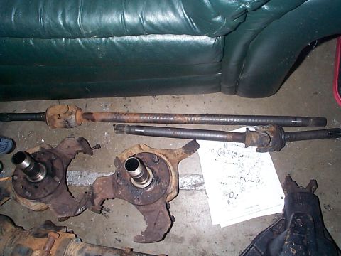 1981 Ford Bronco - Various vehicle axle components are displayed on the floor, possibly for repair or modification.