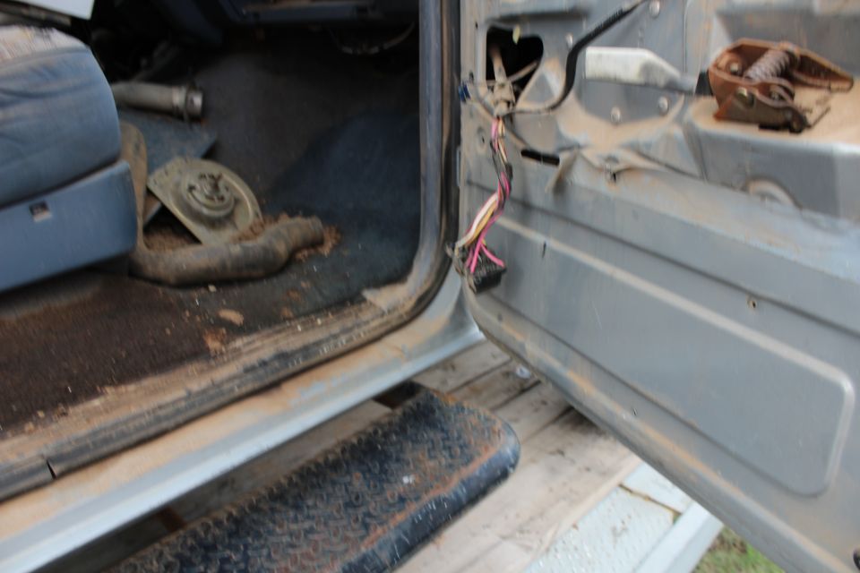 Interior of a vehicle with door open, showing exposed wiring and a step.
