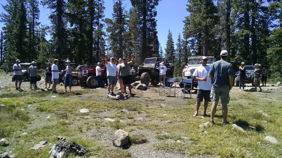Group of people with off-road Jeeps in a wooded area.