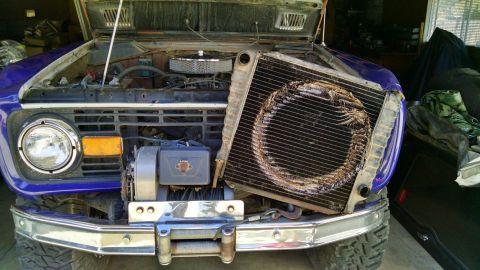 1985 Jeep CJ7 - The front end of a purple SUV is shown with the hood open, revealing a damaged radiator. A winch is mounted on the chrome bumper.