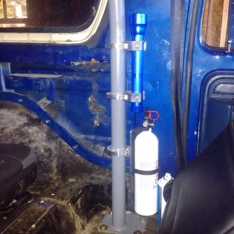 1978 Ford Bronco - Interior view of a blue vehicle showing a gray roll bar with a blue flashlight and a white fire extinguisher mounted to it. A black seat is…