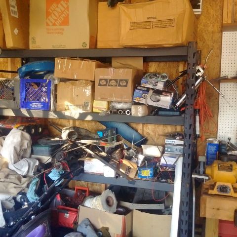 1978 Ford Bronco - This is a cluttered garage shelf filled with various items including boxes, tools, and what appears to be vehicle parts. The shelves are pa…