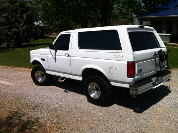 White Ford Bronco parked on gravel, rear passenger side view.