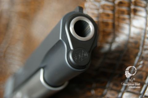 1979 Ford Bronco - A close-up, low-angle shot of the muzzle of a pistol. The pistol has a dark gray slide and barrel, with a silver-colored barrel opening. A…
