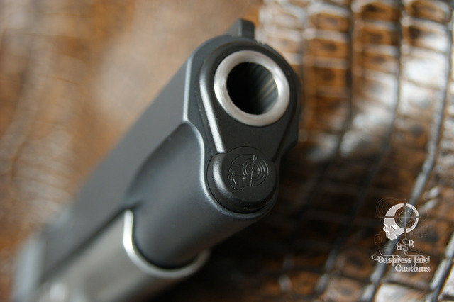 Close-up of a pistol muzzle with a skull and crosshairs logo.