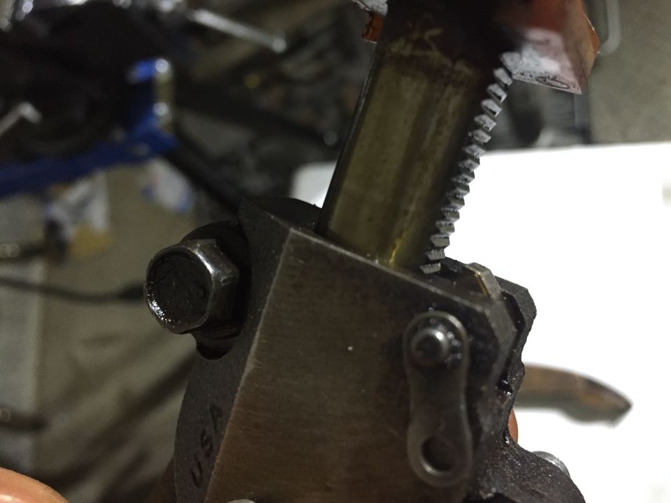 Close-up of a thread tap cutting a metal shaft in a steel tool holder marked USA, in a garage