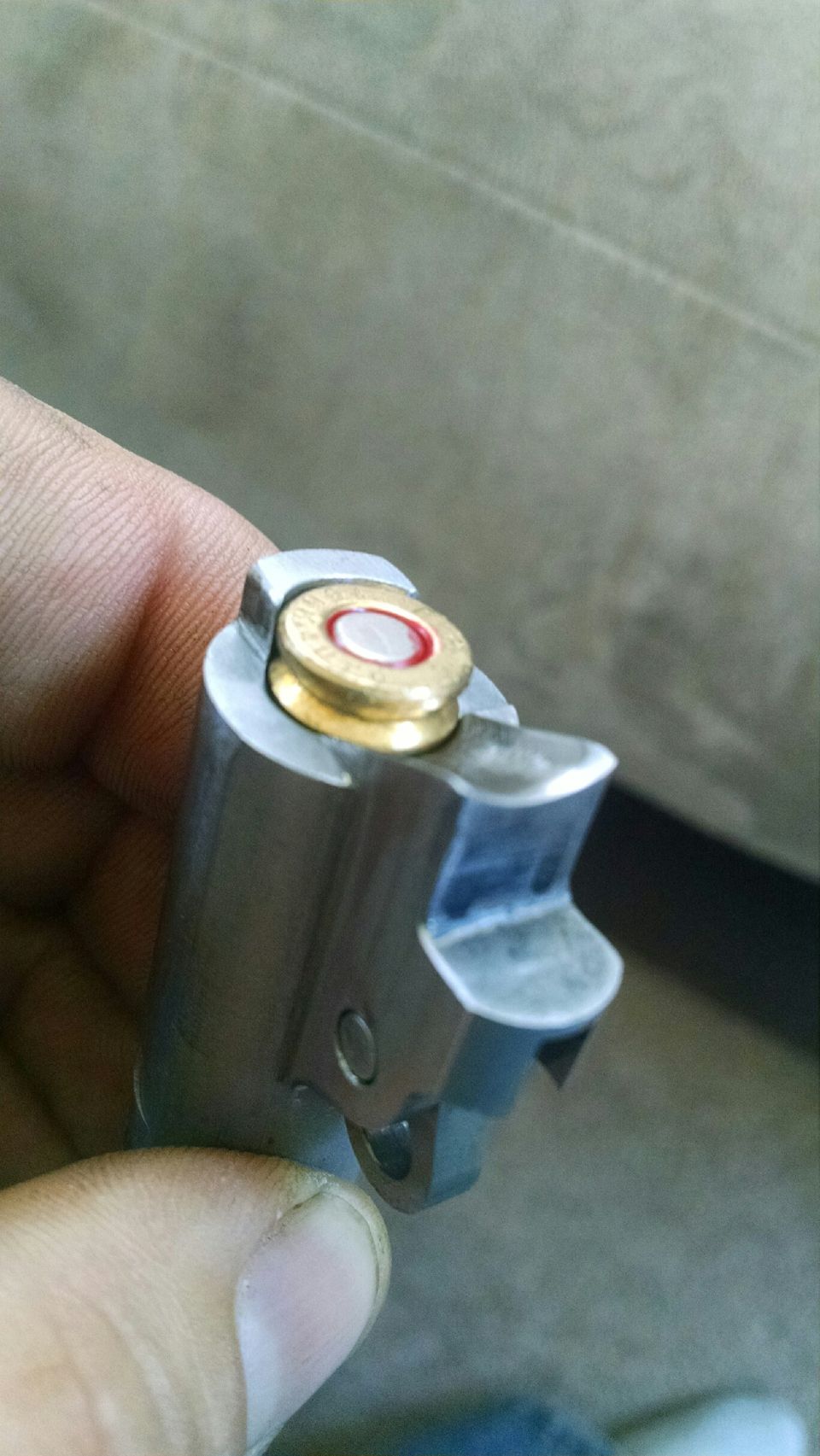 Close-up of a gun cylinder holding a brass bullet with a red primer