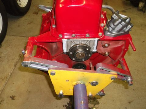 1957 Ford Custom Sedan - Close-up of a red engine block and transmission bell housing assembly, mounted on a stand. The Supermotors.net logo is visible in the lower…