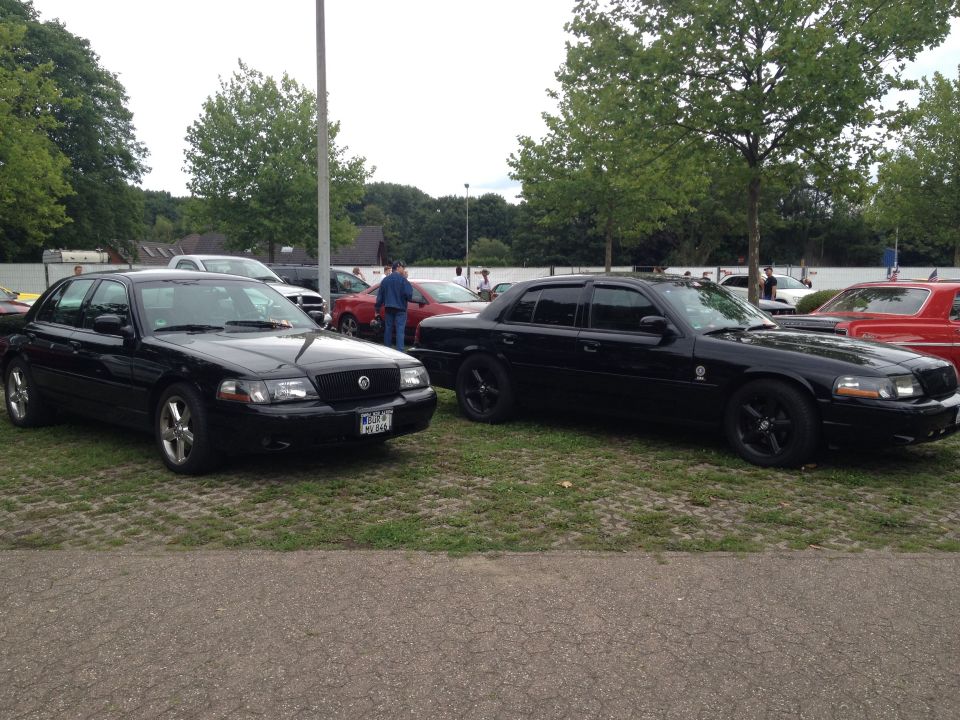 Two black sedans parked on grass. One is a 2003 Mercury Marauder