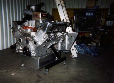1963 Ford Fairlane - Engine on a stand in a workshop setting, with a shopping cart and ladder in the background.