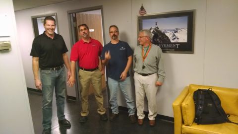 1971 Ford Ranchero - Four men pose for a photo in an office hallway, with a motivational poster reading 'ACHIEVEMENT' visible on the wall.