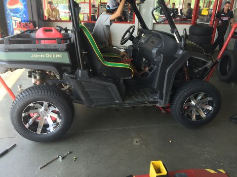 1988 Ford Bronco - A John Deere Gator UTV is shown on a lift in a service bay with custom wheels.
