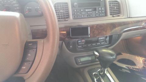 2000 Mercury Grand Marquis - The dashboard of a 2000 Mercury Grand Marquis features wood grain trim and a mounted GPS unit.