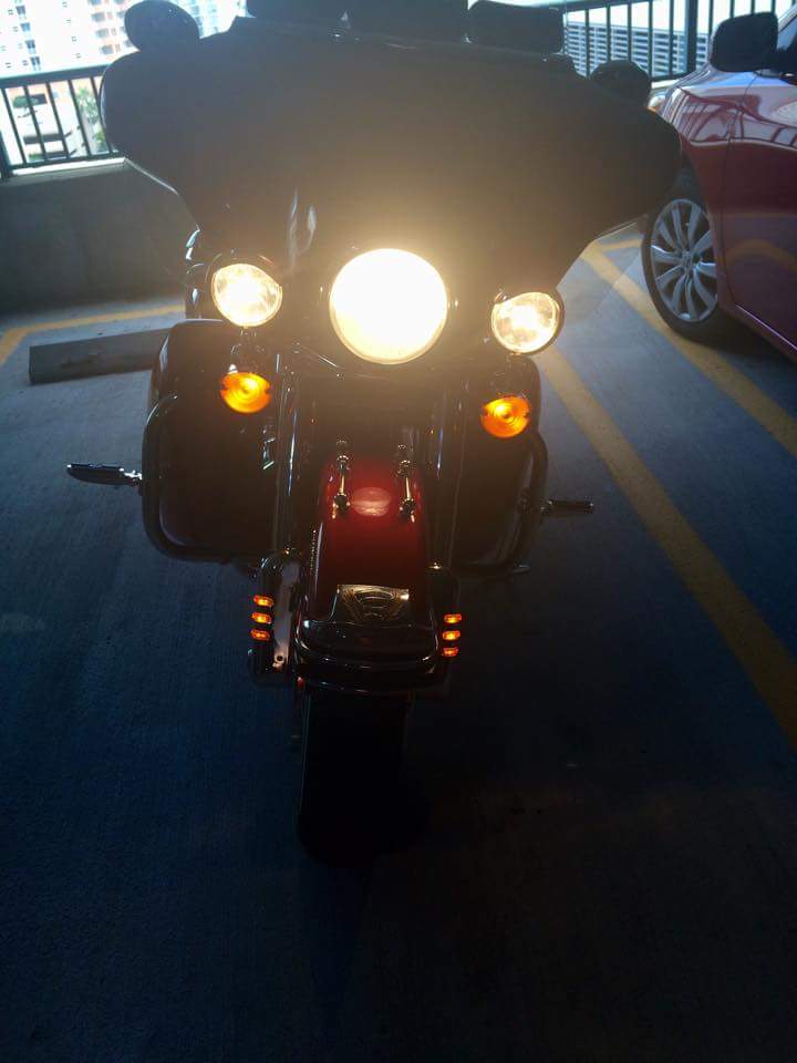 2014 Harley-Davidson FXDWGI Wide Glide motorcycle, front view, headlights on, parked next to a red car