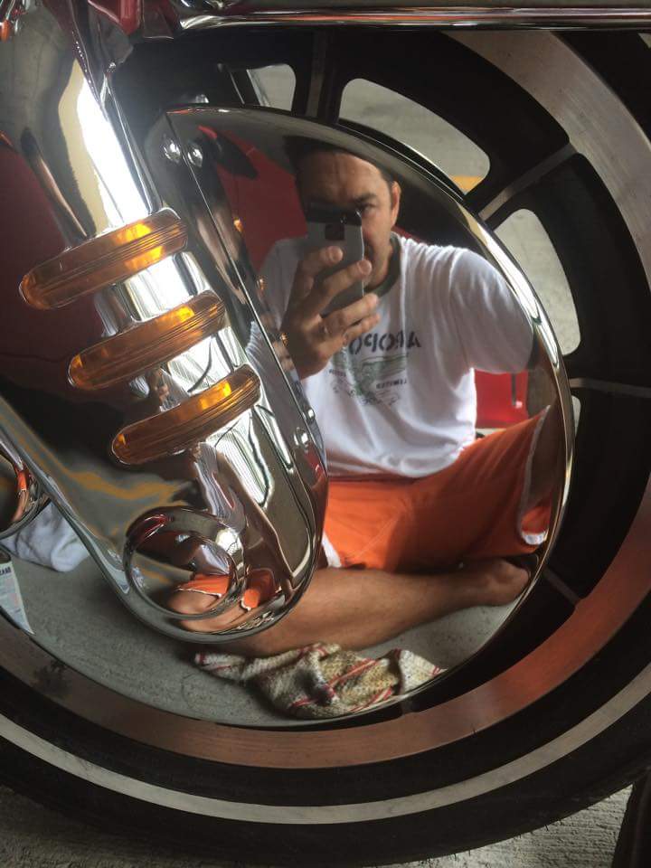 Chrome fender with amber turn signals reflected in a motorcycle wheel