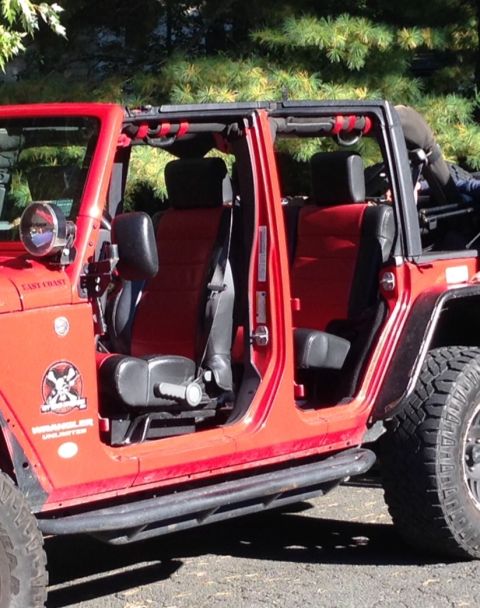 1979 Ford Bronco - A red Jeep Wrangler is shown with its doors off, revealing the interior seating and roll cage.